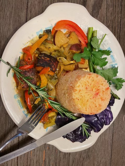 Beautifully plated Caribbean dish with rice, stewed meat, and fresh herbs